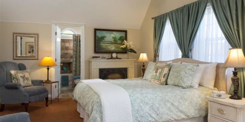 photo shows window behind bed frame with wall painting and electric fireplace