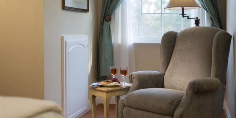 photo of arm chair with side table holding two glasses of wine